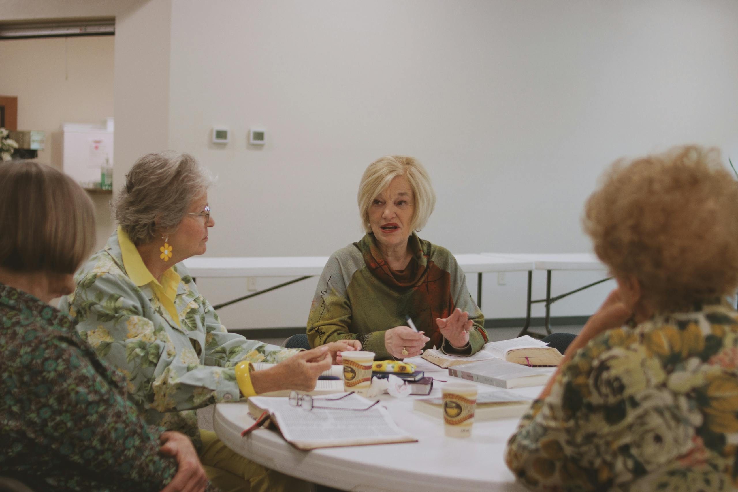 An intergenerational group of women engaged in a Bible study session indoors.