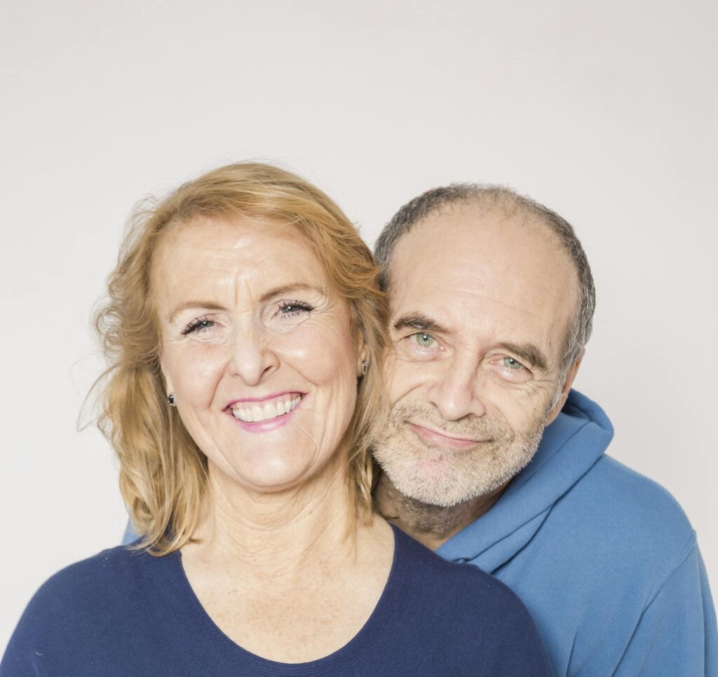 Heartwarming studio portrait of a joyful elderly couple embracing and smiling.